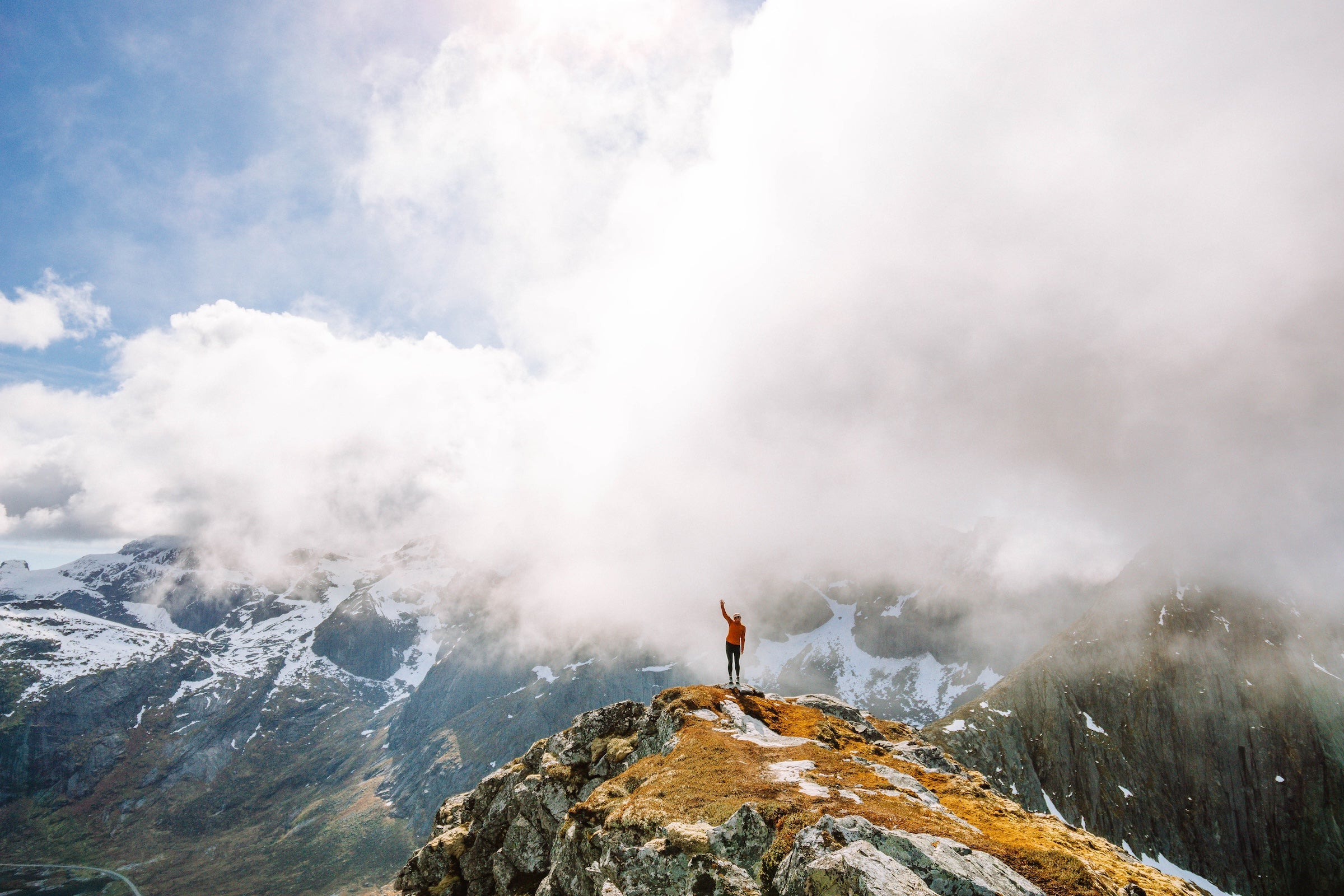 Person standing on a mountain peak with clouds below