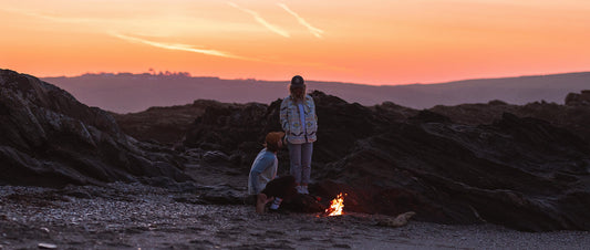 Two people by a firepit on the beach