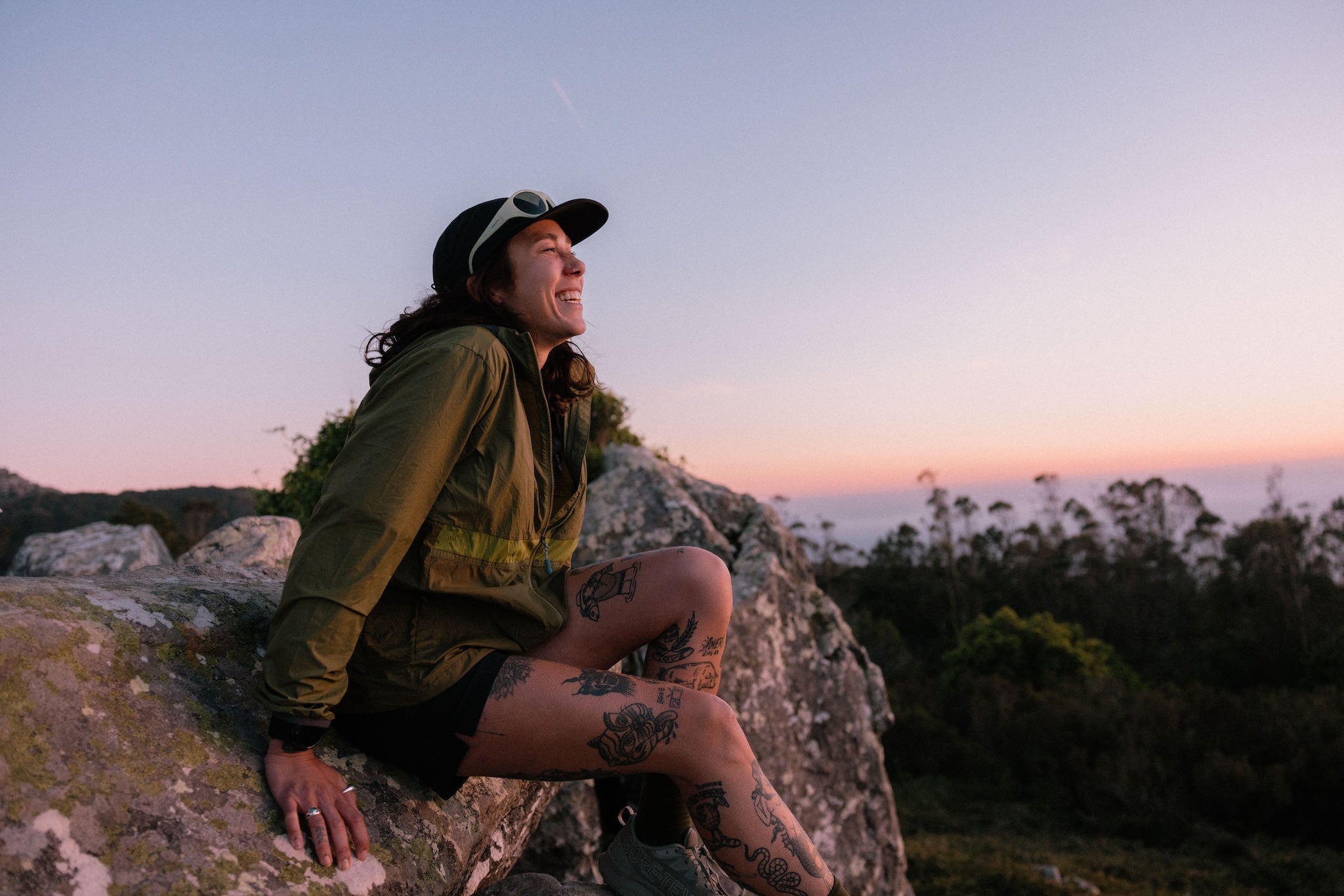 A woman sat on a rock at sunset, smiling